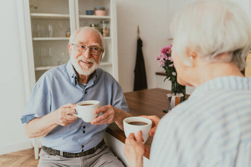 Senior couple having breakfast at home - Elderly people daily life in the moning - DMDF02524