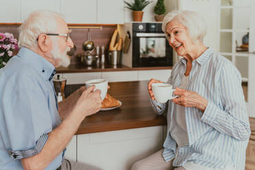 Senior couple having breakfast at home - Elderly people daily life in the moning - DMDF02525