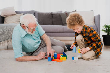 Grandparents and grandson playing at home - Family at home, grandfather taking care of nephew - DMDF02540