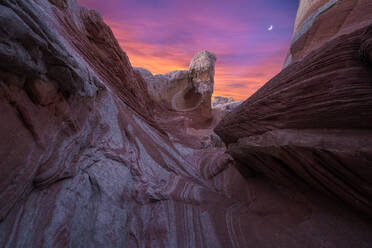 Picturesque scenery of rough rocky mountains under cloudy purple and orange sky at sundown in evening - ADSF46621