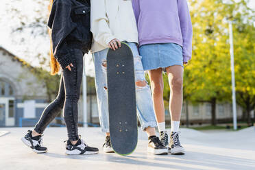 Multicultural group of young friends bonding outdoors and having fun - Stylish cool teens gathering at urban skate park - DMDF02570