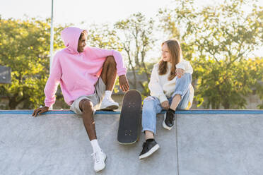Multicultural group of young friends bonding outdoors and having fun - Stylish cool teens gathering at urban skate park - DMDF02574