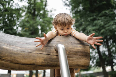 Verängstigter Junge spielt auf einem Spielgerät im Park - ANAF01932