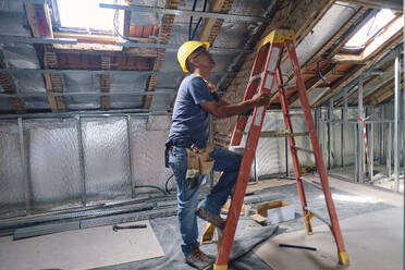 Bauarbeiter steigt auf der Baustelle auf eine Leiter - ASGF04289