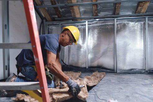 Mature construction worker working on insulation at site - ASGF04297