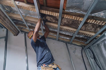 Bauarbeiter beim Anbringen von Dämmmaterial an der Dachgeschossdecke - ASGF04300
