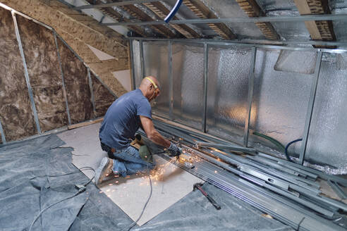 Construction worker cutting metal with hand saw - ASGF04314