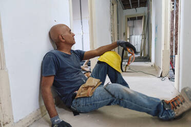 Müder Bauarbeiter entspannt sich im Korridor - ASGF04320