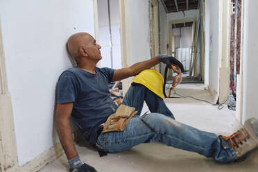 Tired construction worker relaxing in corridor - ASGF04320