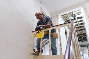 Mature construction worker leaning on railing at site - ASGF04321