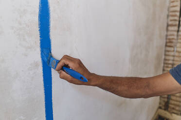 Hand of construction worker applying blue paint on wall - ASGF04339