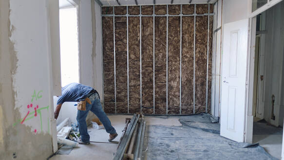 Construction worker working in front of insulation wall at site - ASGF04341