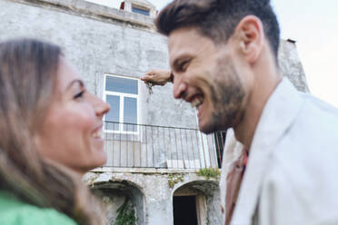 Happy woman with man holding keys in front of house - ASGF04359