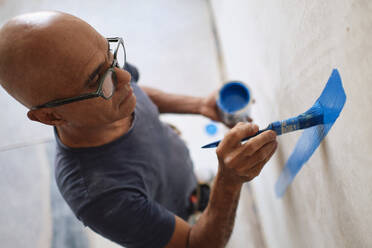 Construction worker painting wall with brush at site - ASGF04407