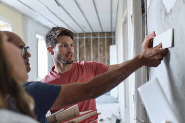 Man and woman discussing over samples with construction worker at site - ASGF04434