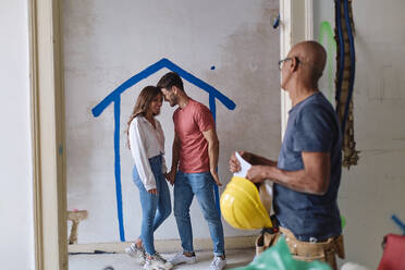 Construction worker with man embracing woman at site - ASGF04436