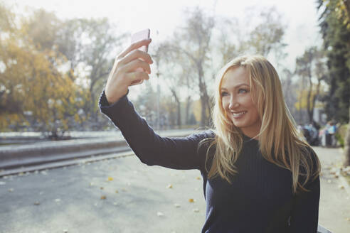 Smiling woman taking selfie through smart phone - AZF00562