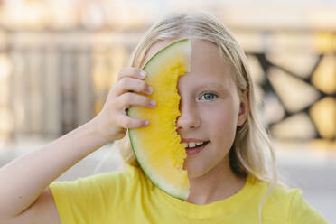 Lächelndes Mädchen bedeckt ihr Gesicht mit gelber Wassermelone - SIF00802