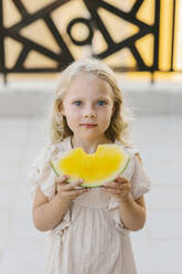 Mädchen mit Scheibe gelber Wassermelone in den Händen auf der Straße - SIF00805