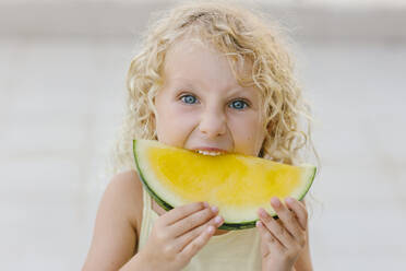 Blond girl biting slice of yellow watermelon - SIF00807