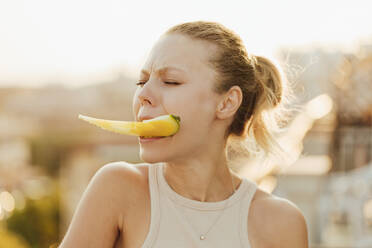 Frau hält ein Stück gelbe Wassermelone zwischen ihren Zähnen - SIF00809