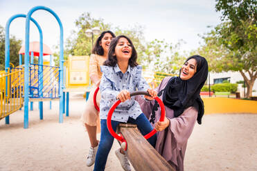 Happy arabian family having fun in Dubai - Mom together with her daughters in park play area - DMDF02603