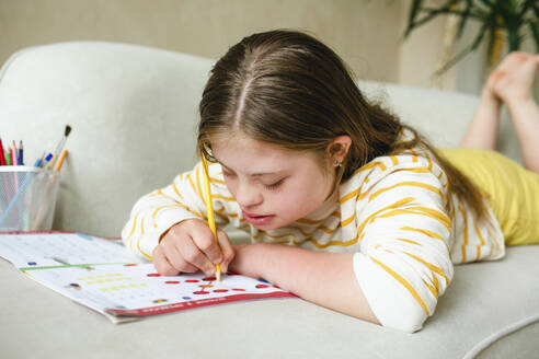 Teenager-Mädchen mit Down-Syndrom macht zu Hause Hausaufgaben - MDOF01419