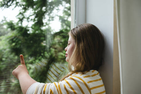 Teenage girl with down syndrome touching window glass - MDOF01426