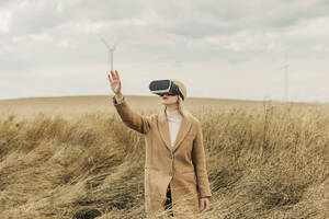 Frau trägt Virtual-Reality-Simulatoren und gestikuliert in einem Feld - VSNF01301