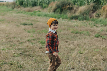 Glücklicher Junge mit Strickmütze auf einem Feld - VSNF01305