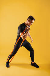 Athletic man with fit muscular body training in studio - Active man doing a workout, colorful lighting and background, concepts about fitness, sport and health lifestyle - DMDF02632