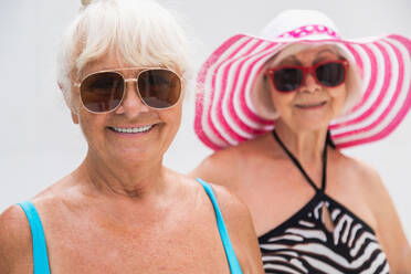 Happy senior women having party in the swimming pool - Elderly friends relaxing at a pool party - DMDF02636