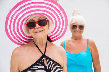 Happy senior women having party in the swimming pool - Elderly friends relaxing at a pool party - DMDF02637