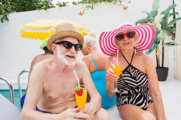 Happy seniors having party in the swimming pool - Elderly friends at a pool party during summertime - DMDF02658