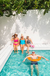 Happy seniors having party in the swimming pool - Elderly friends at a pool party during summertime - DMDF02686