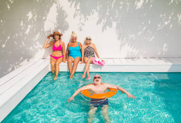 Happy seniors having party in the swimming pool - Elderly friends at a pool party during summertime - DMDF02687