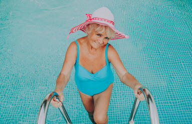 Glückliche ältere Frau mit Party im Schwimmbad - Schöne ältere Dame Sonnenbaden und Entspannen in einem privaten Pool während der Sommerzeit - DMDF02702