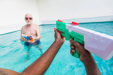 Happy seniors having party in the swimming pool - Elderly friends at a pool party during summertime - DMDF02711