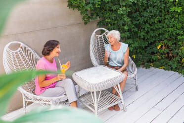 Beautiful senior women relaxing at home in the garden - Two pretty mature ladies rest in a peaceful backyard garden - DMDF02716