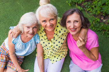 Beautiful senior women relaxing at home in the garden - Three pretty mature ladies rest in a peaceful backyard garden - DMDF02725