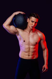 Athletic man with fit muscular body training in studio - Active man doing a  workout, colorful lighting