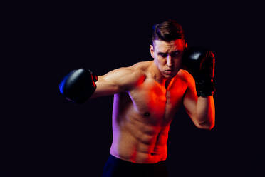 Athletic man with fit muscular body training in studio - Active man doing a workout, colorful lighting and background, concepts about fitness, sport and health lifestyle - DMDF02738