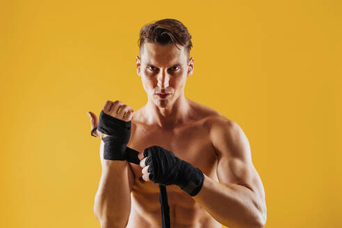 Athletic man with fit muscular body training in studio - Active man doing a workout, colorful lighting and background, concepts about fitness, sport and health lifestyle - DMDF02746