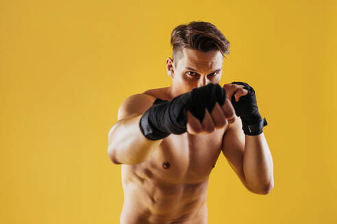 Athletic man with fit muscular body training in studio - Active man doing a workout, colorful lighting and background, concepts about fitness, sport and health lifestyle - DMDF02747