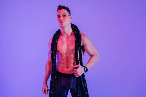 Athletic man with fit muscular body training in studio - Active man doing a workout, colorful lighting and background, concepts about fitness, sport and health lifestyle - DMDF02753