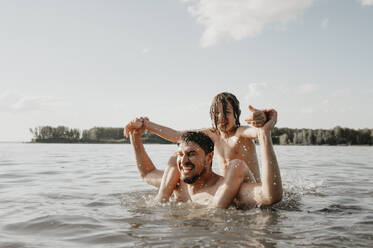 Happy father with son enjoying in sea on sunny day - ANAF01950