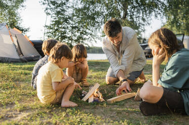 Children with father preparing for bonfire on grass - ANAF01962