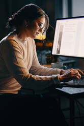 Entschlossene Geschäftsfrau, die in einem Büro zu später Stunde unermüdlich auf ihrem Laptop tippt. Berufstätige Frau, die darauf hinarbeitet, eine Frist für ein Projekt zum Schreiben von Webinhalten einzuhalten. - JLPSF30738