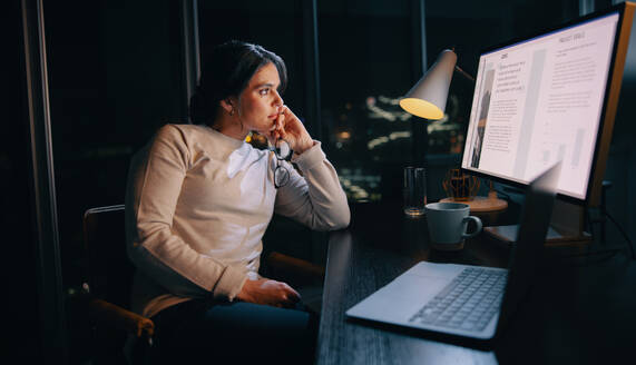 Businesswoman working late at her home office, deeply engaged in a digital marketing project on her computer. Woman putting in dedication and long hours into her social media marketing profession. - JLPSF30756