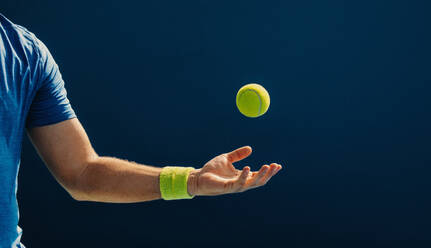 Ein geübter Tennisspieler fängt einen Ball in der Luft mit einer Hand und zeigt dabei Athletik und Konzentration auf das Spiel. Ein sportlicher Mann spielt ein Tennismatch auf dem Platz. Bei diesem Foto wurde absichtlich das Korn eines 35-mm-Films verwendet. - JLPPF02372